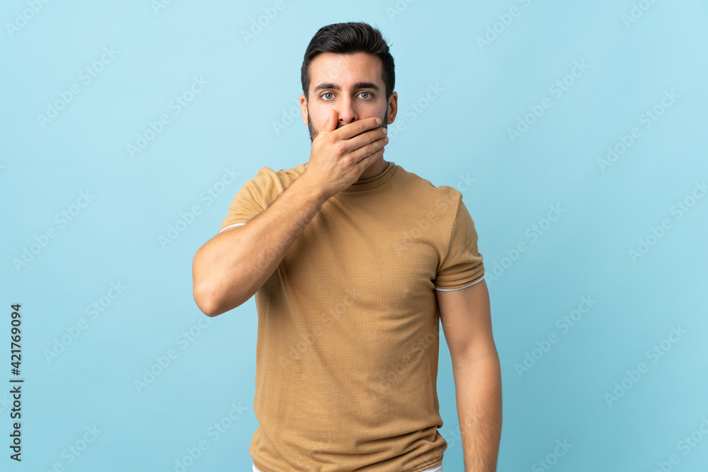 Young handsome man with beard over isolated background covering mouth with hand Young handsome man with beard over isolated background covering mouth with hand