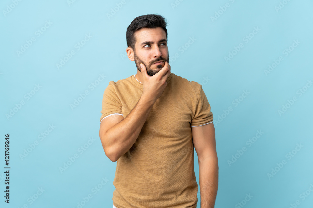 Young handsome man with beard over isolated background having doubts and with confuse face expression Young handsome man with beard over isolated background having doubts and with confuse face expression