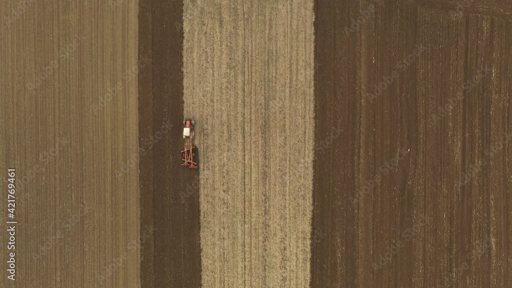 Above top view shot of tractor, he is pulling machine, harrowing arable field, preparing soil for planting new crop next season. Above top view shot of tractor, he is pulling machine, harrowing arable field, preparing soil for planting new crop next season.