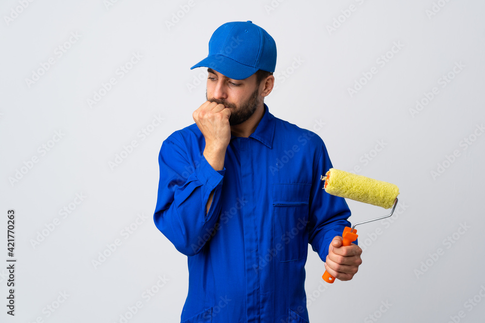 Painter man holding a paint roller isolated on white background having doubts Painter man holding a paint roller isolated on white background having doubts