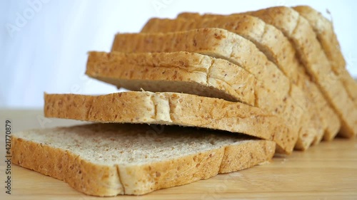 Close up slow motion of falling whole wheat bread sliced on wooden table