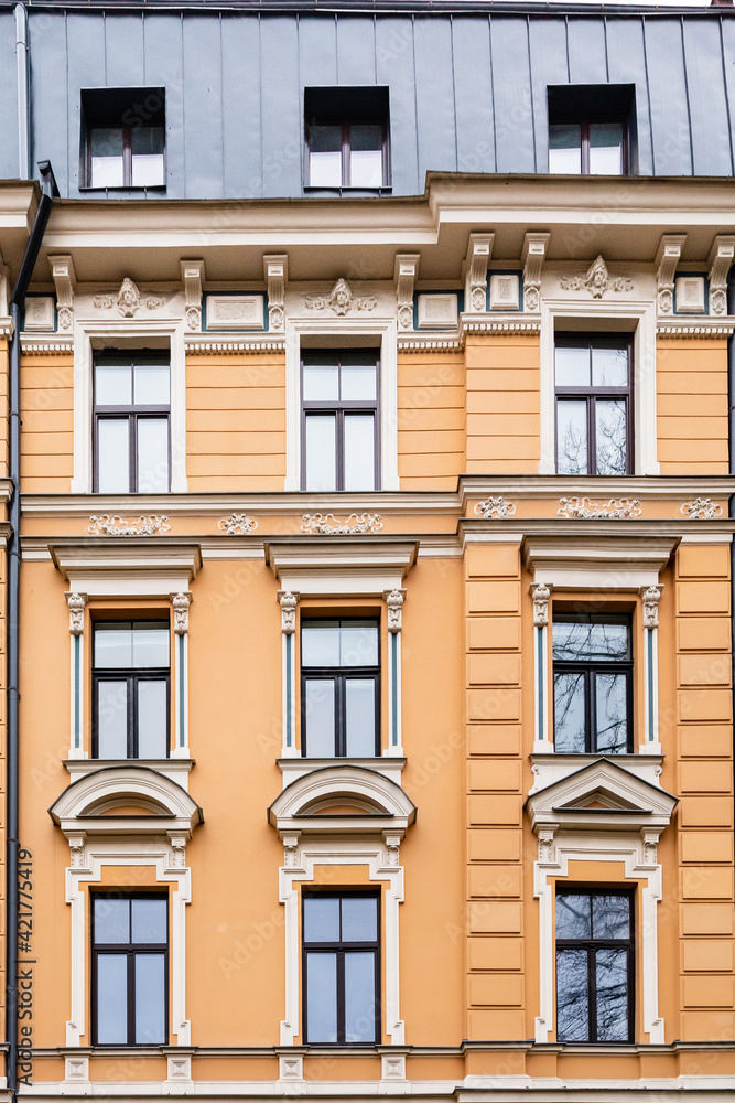 Orange brick art nouveau building façade with nine cream windows in Riga, Latvia, Europe
