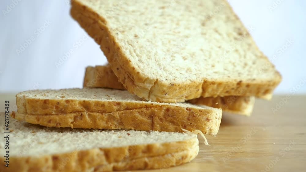 Close up slow motion of falling whole wheat bread sliced on wooden table Close up slow motion of falling whole wheat bread sliced on wooden table