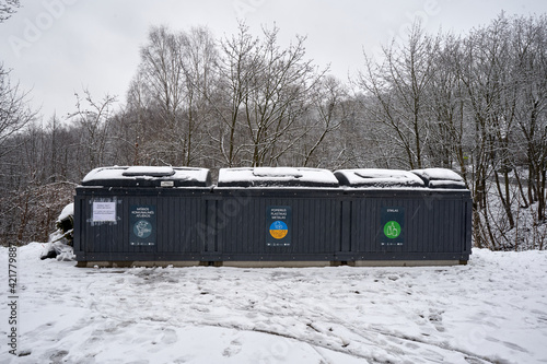 Half underground trash containers in Vilnius covered with wet snow