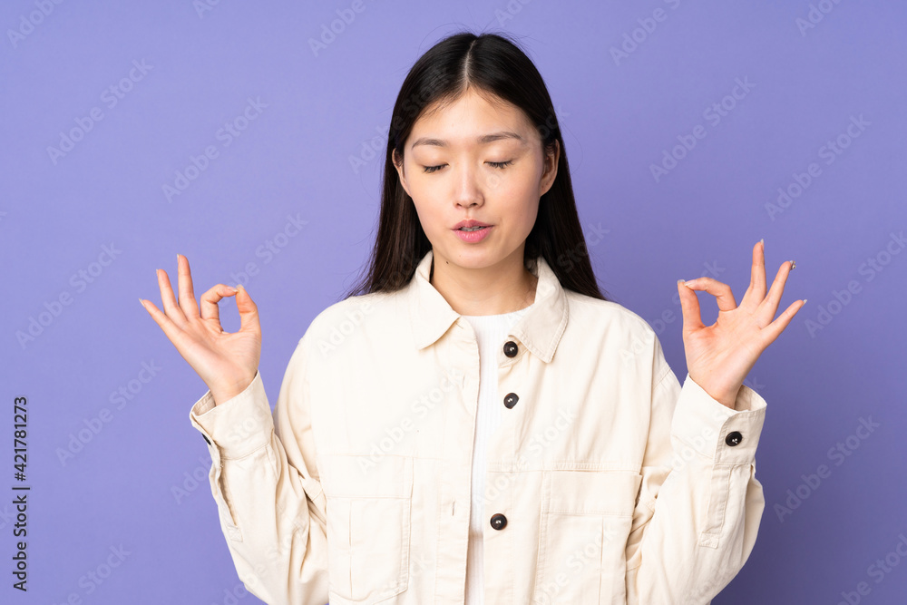Young asian woman isolated on purple background in zen pose Young asian woman isolated on purple background in zen pose