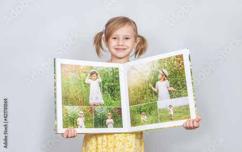 A Little girl holding a photobook with her photographs in her handspt