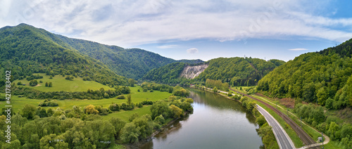 Village, river and road in mountain valley. Green mountain meadows and hills