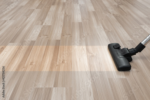 Clean strip and vacuum cleaner on the wooden floor near the copy space