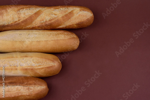 French baguettes isolated on a brown background top view stock images. Pile of french bread still life frame stock photo. Fresh baguettes on a brown background with copy space for text