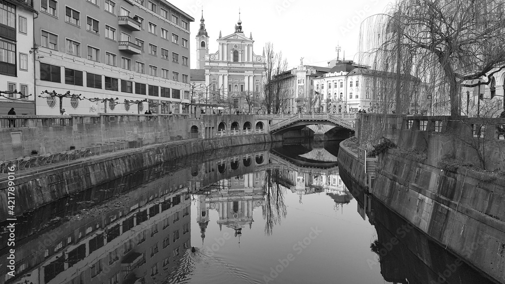 Black & white photo of Ljubljanica river with Tromostovje - famous three bridges in centre of Ljubljana, Slovenia created by architect Plečnik