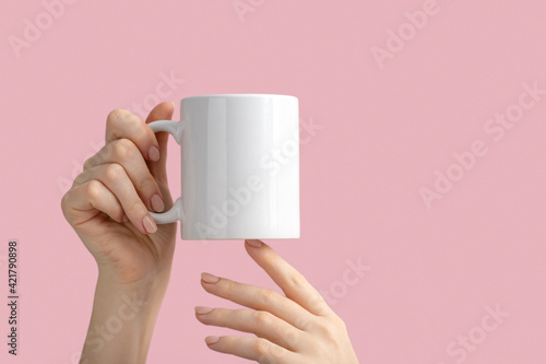 mockup white coffe cup or mug in female hands on pink background with copy space. Blank template for your design, branding, business. Real photo photo