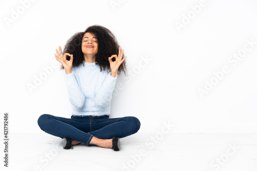 Young african american woman sitting on the floor in zen pose