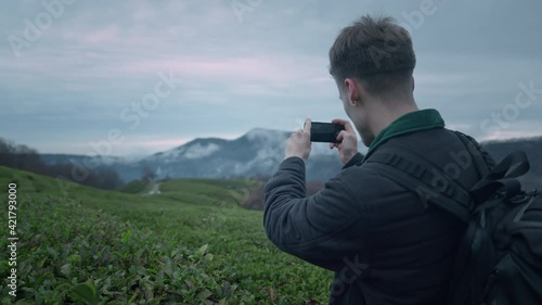 Photographer shots beautiful sunset with phone on the tea plantation photo