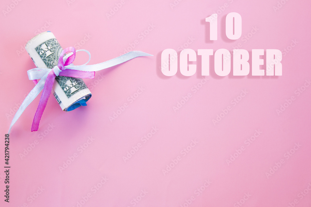 calendar date on pink background with rolled up dollar bills pinned by pink and blue ribbon with copy space. October 10 is the tenth day of the month
