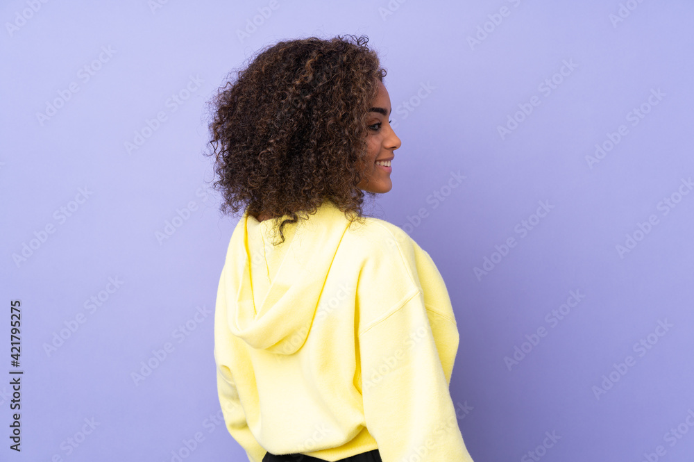 Young African American woman isolated on background in back position and looking side Young African American woman isolated on background in back position and looking side