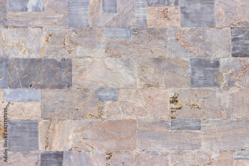 Fototapeta premium The surface of the wall of the building, made of hewn marble blocks of different sizes and colors.