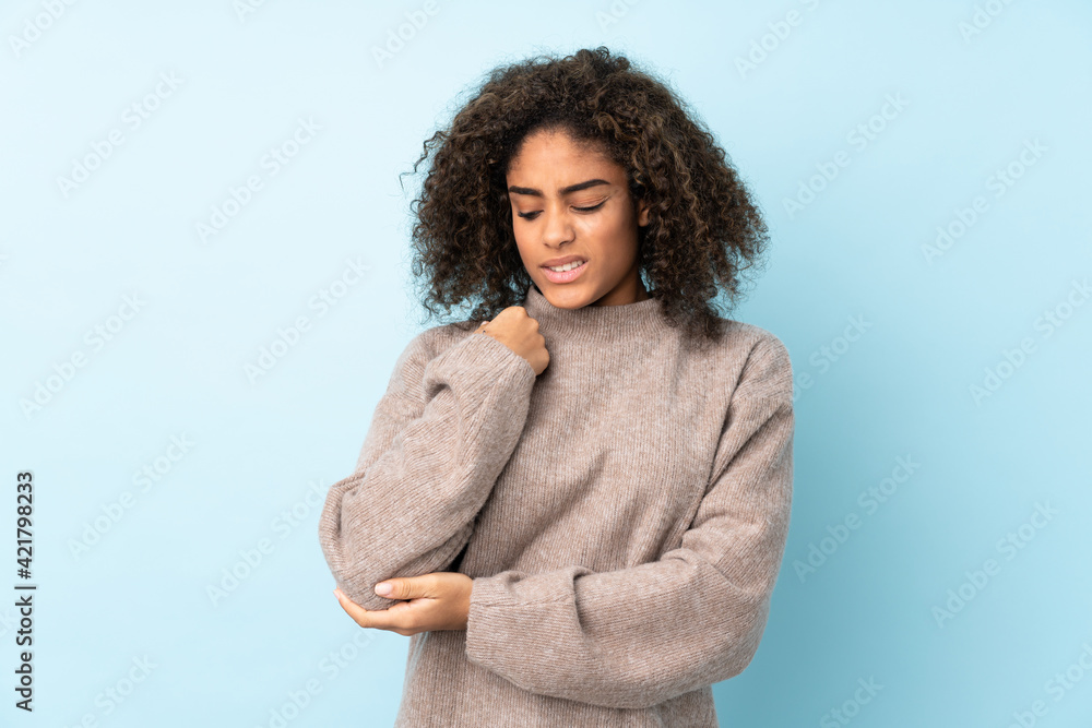 Young African American woman isolated on blue background with pain in elbow Young African American woman isolated on blue background with pain in elbow