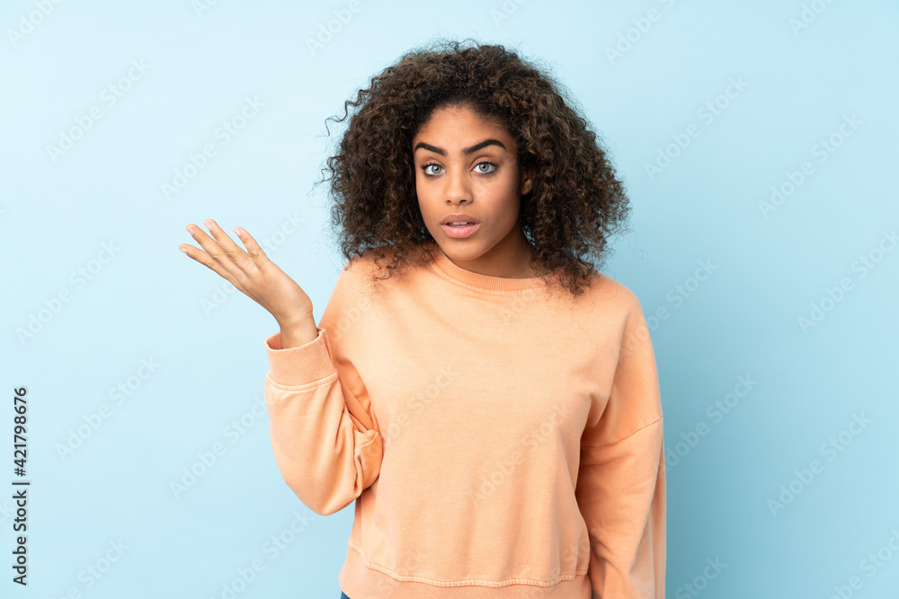 Young African American woman isolated on blue background making doubts gesture Young African American woman isolated on blue background making doubts gesture