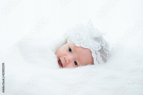 0-1 month Asian newborn baby lie down on white fur background or soft blanket, toddler infant open eye after long sleeping, baby make funny face smiling play alone, tiny infant in studio