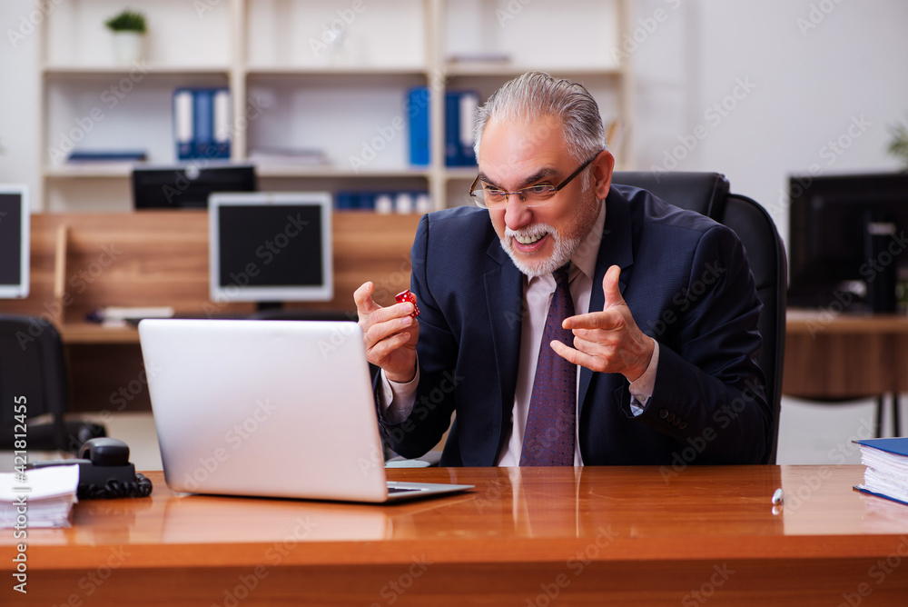 Old male employee in gambling concept at workplace Old male employee in gambling concept at workplace