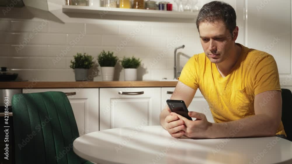 Man using a smartphone in the kitchen. Man using a smartphone in the kitchen.