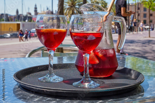 Photography Jug and glasses with sangria beverage on the table in street cafe in center of Barcelona