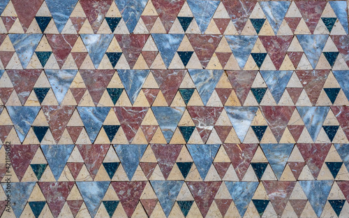 Stone floor with geometric pattern of triangular colored marble tiles.