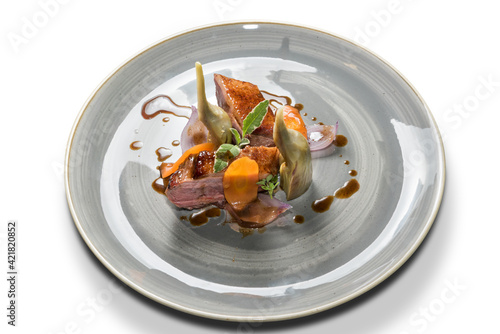 Roasted duck breast with artichokes, sage and carrots in a gray plate isolated on a white background