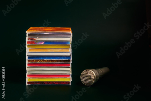 Audio microphone with CDs on a dark green background.