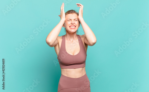 young blond woman feeling stressed and anxious, depressed and frustrated with a headache, raising both hands to head. sport concept