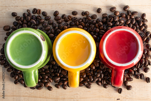 Canvas Print upside down red, green, yellow cups with coffee beans on wood