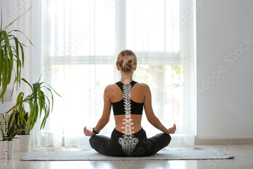 Young woman with good posture meditating at home, back view photo