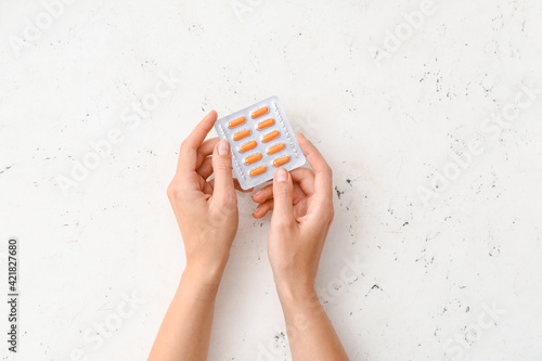 Fotografia Female hands and blister pack with turmeric pills on light background