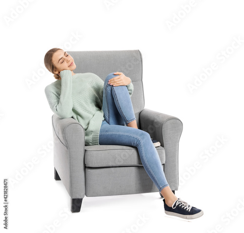 Young woman relaxing in armchair on white background