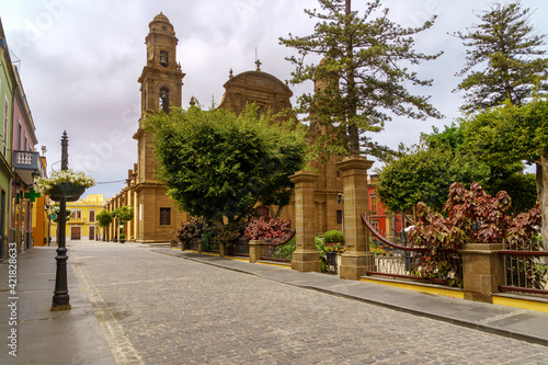 Old church next to a park with green plants and cobbled streets. Galdar Gran Canaria.