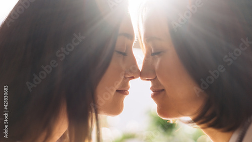Close-up Portrait Shot of Happy Lesbian Couple Pressing Their Noses Together at Home. Two Lovely Girls Spending Time Together, Enjoying Sunny Day. Authentic Tender Moments Between Lovely Girlfriends.