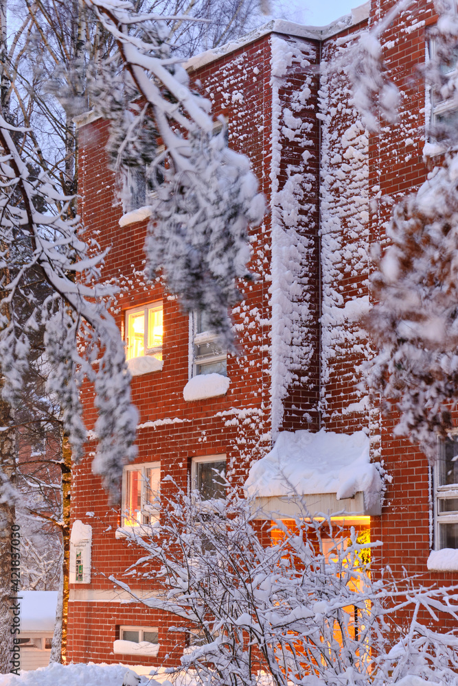 The snow-covered red brick wall of the residential apartment building after a strong snow-storm in Finland.