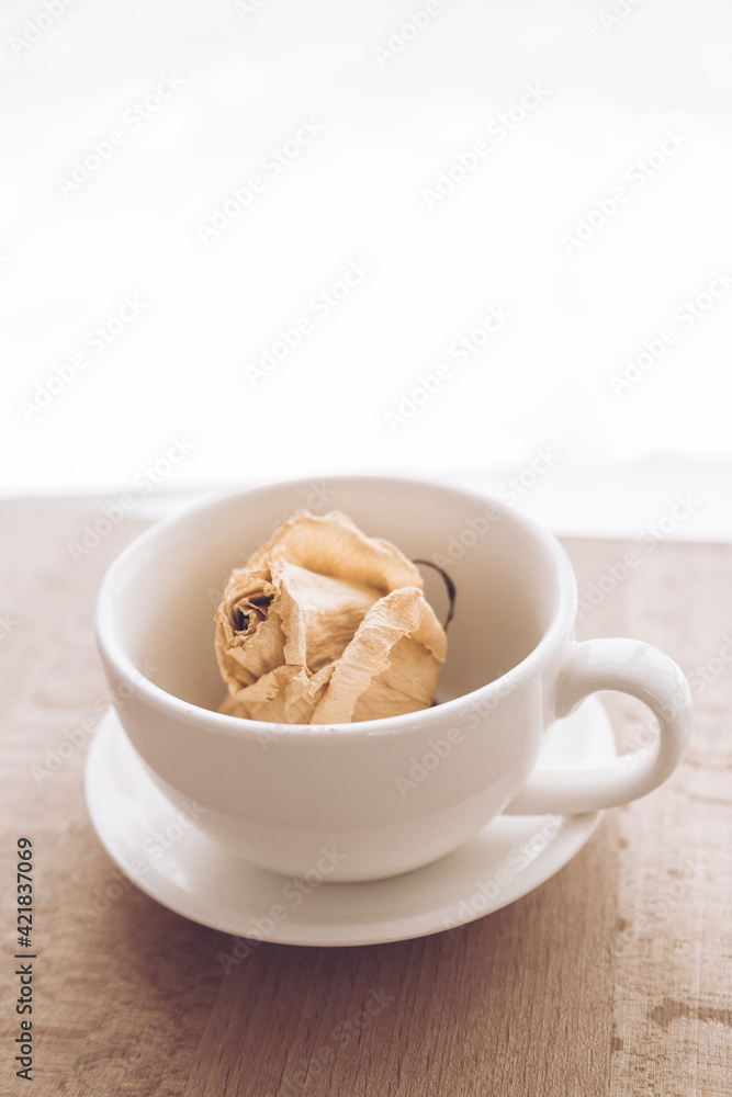 A small cup for tea with a saucer on the background of a beautiful view from the window. A cup for coffee with a flower bud inside. A small cup for tea with a saucer on the background of a beautiful view from the window. A cup for coffee with a flower bud inside.