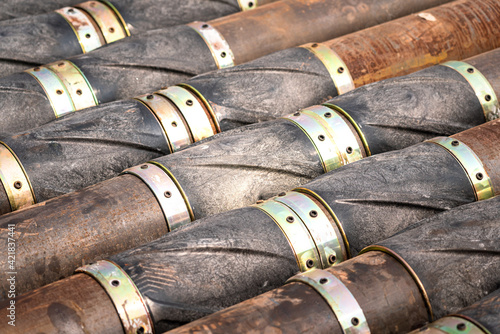 Stack of heavy steel drill pipe with reamer part that prepared for drilling to crude oil well in energy exploration industrial. Close-up and selective focus at center. Industrial object and equipment. photo