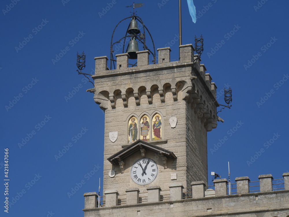 Obraz premium San Marino, Public Palace. Closeup on the crenellated clock tower with the mosaic and the coats of arms of the four Castles of the Republic