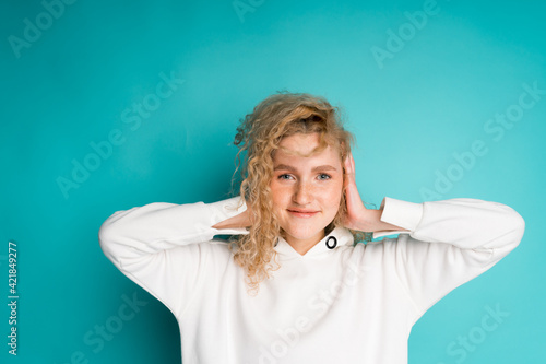 Wallpaper Mural Portrait of a young cute girl who smiles and covers her ears with her hands Torontodigital.ca