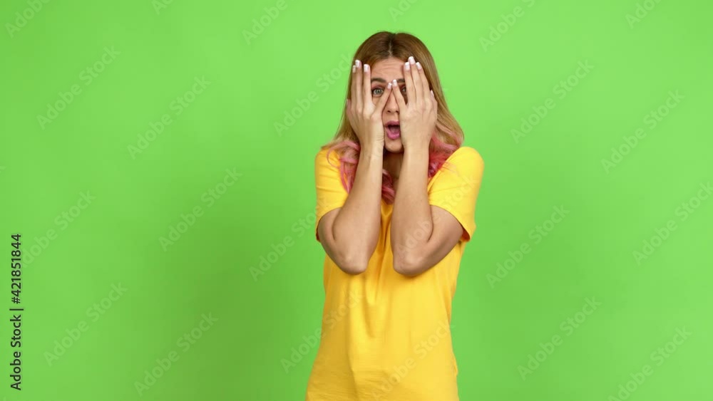 Young blonde woman covering eyes by hands and looking through the fingers over isolated background on green screen chroma key Young blonde woman covering eyes by hands and looking through the fingers over isolated background on green screen chroma key