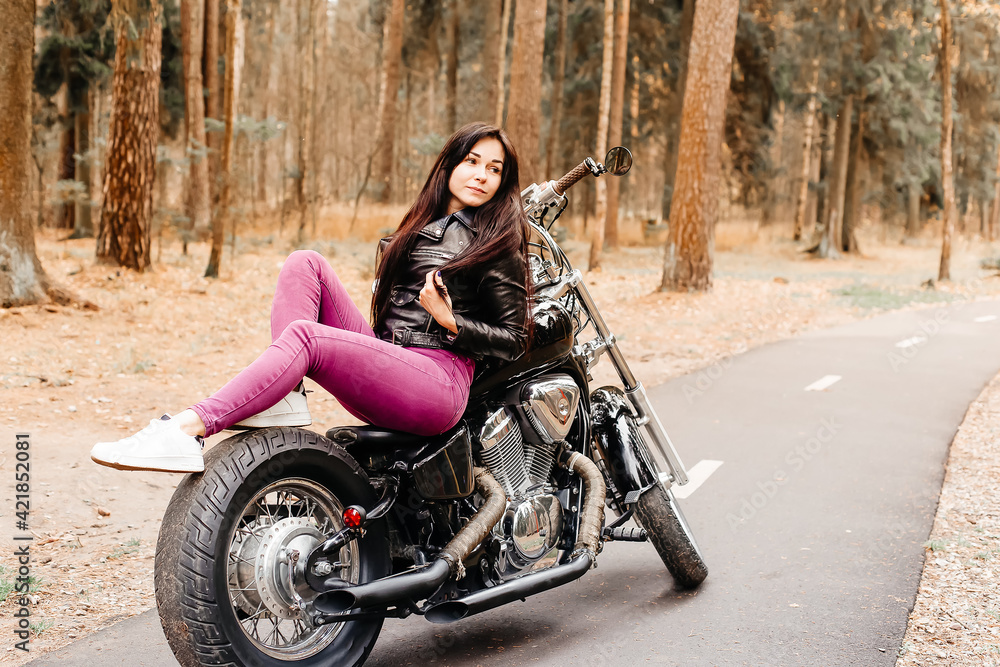 Naklejka premium beautiful brunette riding a motorcycle in the park