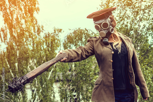 Creepy stalker girl in a gas mask and Soviet police cap, with hand made barbed wire baseball bat. photo