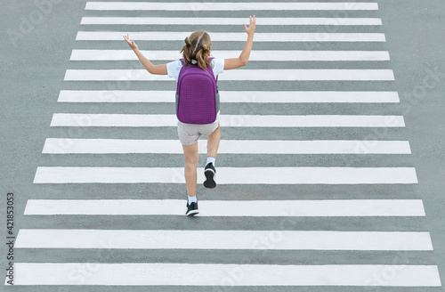 Stylish young teen girl walking with backpack. Active child. Kid runs across the crosswalk. A school child jumps down the street. Way forward. Direction to success. Positive thinking. Top view