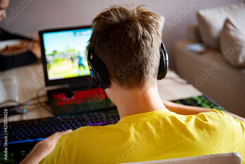 adolescente che gioca su pc ai videogames con cuffie e microfono photo