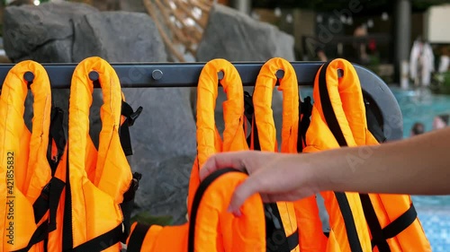 Orange life jackets. Life jackets are neatly hung out in front of the open water pool and are ready to use. Safety on the water.
