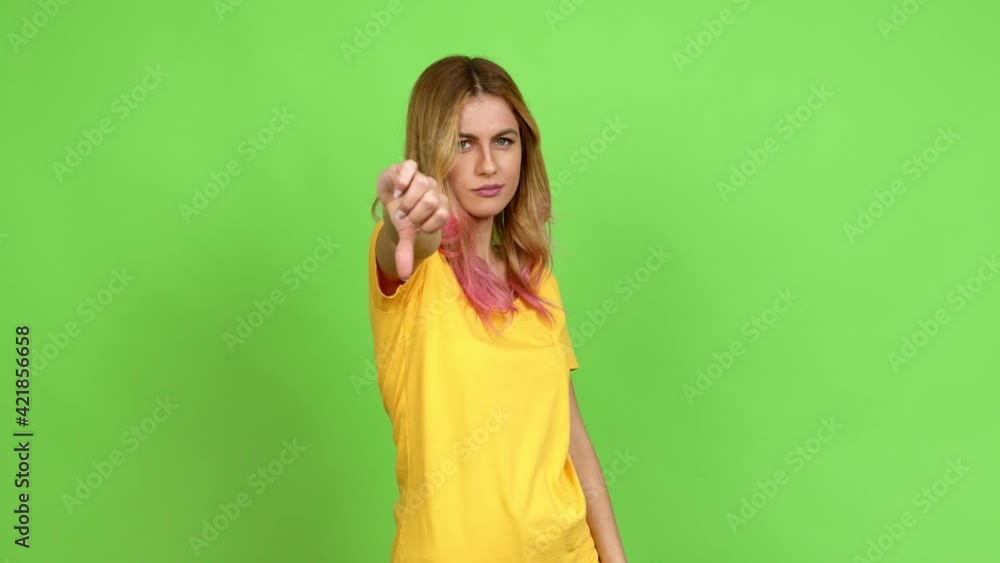 Young blonde woman doing bad signal over isolated background on green screen chroma key Young blonde woman doing bad signal over isolated background on green screen chroma key