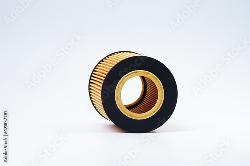 A yellow automobile oil filter with a cover lies on a white background. Replacement filter cartridge for cleaning oil of the car. The filter cover is black.