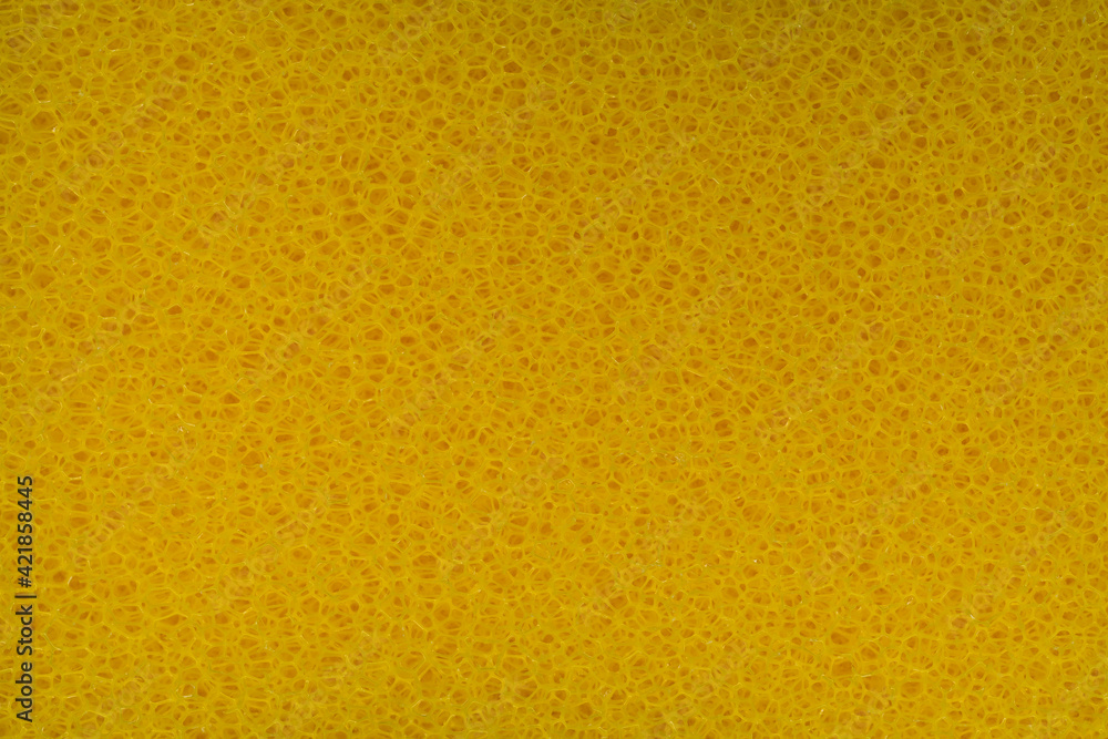 The rough texture of yellow plastic sponge scrubber with holes for background The rough texture of yellow plastic sponge scrubber with holes for background